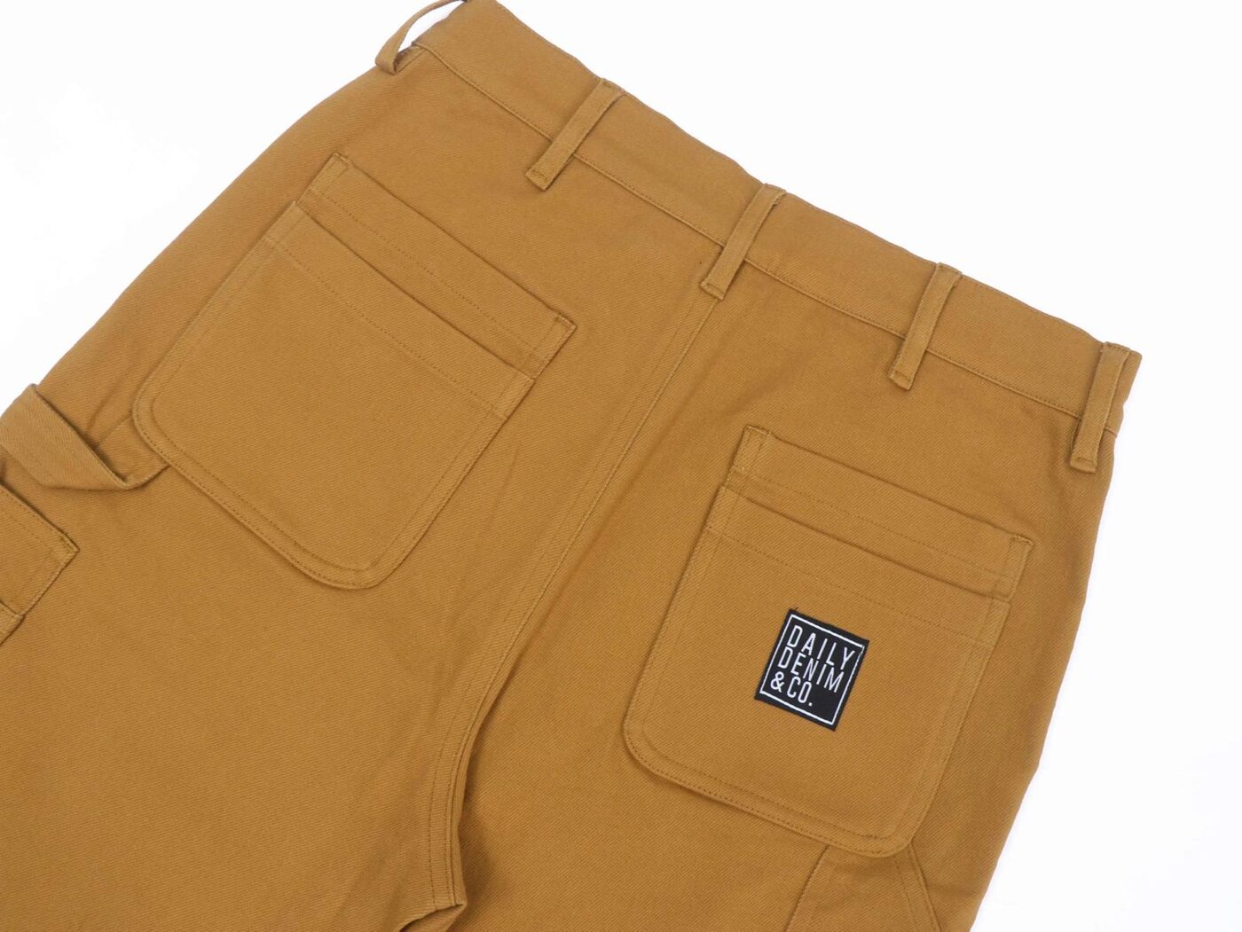 Close-up of Construction Brown utility pant back pockets with the Daily Denim & Co. rubber patch
